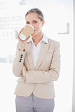 Smiling blonde businesswoman drinking coffee