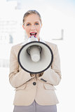 Blonde businesswoman shouting in megaphone
