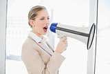 Energetic blonde businesswoman shouting in megaphone