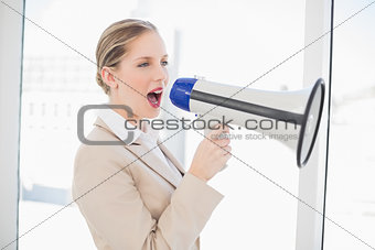 Energetic blonde businesswoman shouting in megaphone