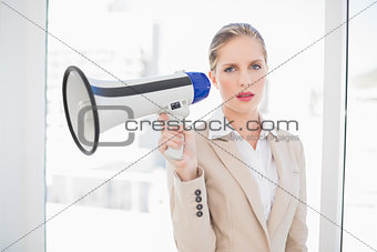 Serious blonde businesswoman holding megaphone