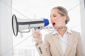 Serious blonde businesswoman screaming in megaphone