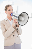 Angry blonde businesswoman screaming in megaphone