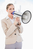 Energetic blonde businesswoman screaming in megaphone