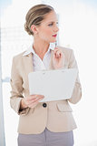 Pensive blonde businesswoman holding clipboard