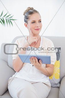 Thinking gorgeous model in white clothes holding tablet pc