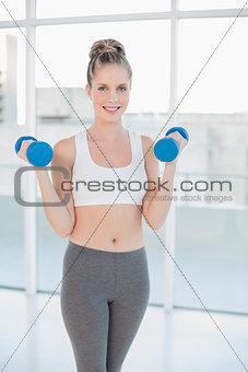 Happy athletic blonde exercising with dumbbells