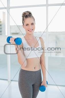 Smiling athletic blonde exercising with dumbbells