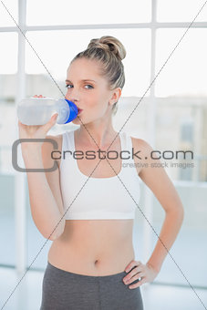 Relaxed sporty blonde drinking water after exercising