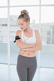 Relaxed sporty blonde wearing armband holding mp3 player