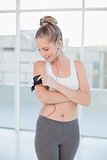 Smiling sporty blonde changing music on her mp3 player