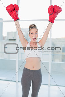 Successful sporty blonde wearing red boxing gloves cheering