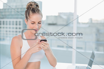 Smiling sporty blonde sending a text