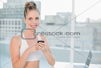 Cheerful sporty blonde sending a text
