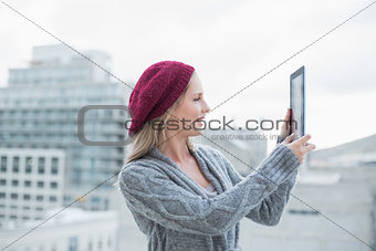 Smiling pretty blonde holding tablet outdoors