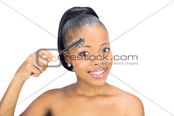 Attractive woman brushing her eyebrow and looking at camera