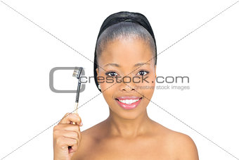 Attractive woman holding eyebrow brush and looking at camera