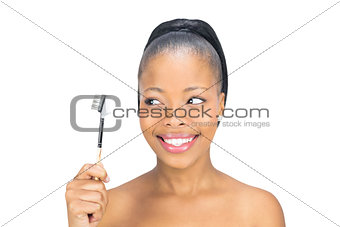 Attractive woman holding and looking at eyebrow brush