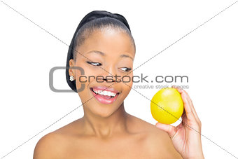 Smiling woman holding and looking at orange