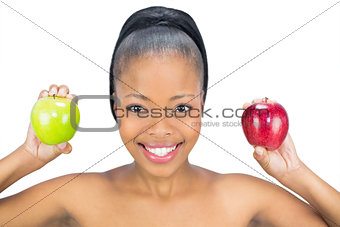 Smiling woman holding red and green apple looking at camera