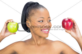Attractive woman holding red and green apple looking at the red one