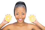 Beautiful woman holding slices of orange and looking at camera