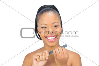 Cheerful woman using nail file while looking at camera