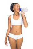 Smiling woman in sportswear drinking water