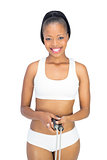 Fit smiling woman in sportswear holding jump rope