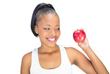Fit woman wearing sportswear looking at red apple