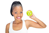 Attractive woman in sportswear showing green apple