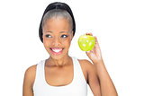 Cheerful woman in sportswear holdig green apple