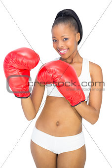 Competitive smiling model wearing red boxing gloves
