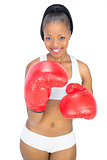 Competitive smiling woman wearing red boxing gloves