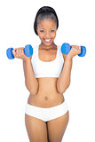 Fit smiling woman working out with dumbbells