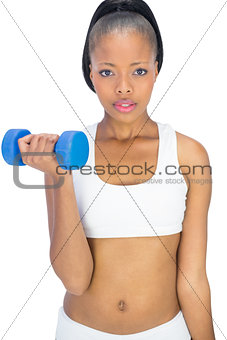 Serious woman in sportswear working out with dumbbell