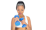 Unsmiling woman in sportswear working out with dumbbells