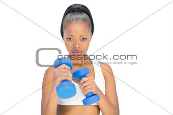 Unsmiling woman in sportswear working out with dumbbells