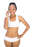 Fit woman in sportswear talking on phone while smiling at camera