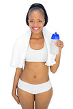 Fit woman with towel around her neck holding sports bottle