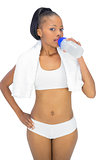 Fit woman with towel around her neck drinking water