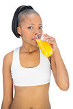Woman in sportswear drinking glass of orange juice