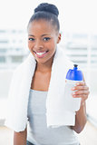 Smiling woman with towel over neck holding sports bottle