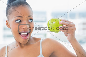Happy woman holding and looking at green apple