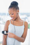 Smiling woman in sportswear listening to music and using her music player