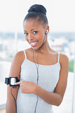 Fit woman in sportswear using her music player while looking at camera
