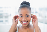 Smiling woman in sportswear touching earphones