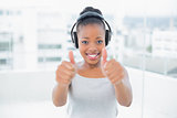 Happy woman listening to music with headphones and giving thumbs up
