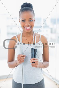 Fit happy woman in sportswear holding jump rope