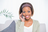 Smiling elegant woman sitting on sofa having a phone call